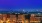 Photograph of the city of Alexandria at night. Yellow lights are illuminating apartment buildings and there are fireworks.